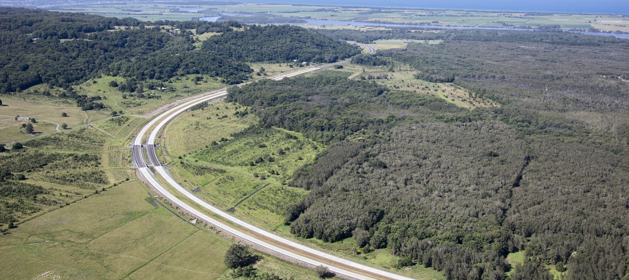 Aerial view of highway with river and ocean in background 